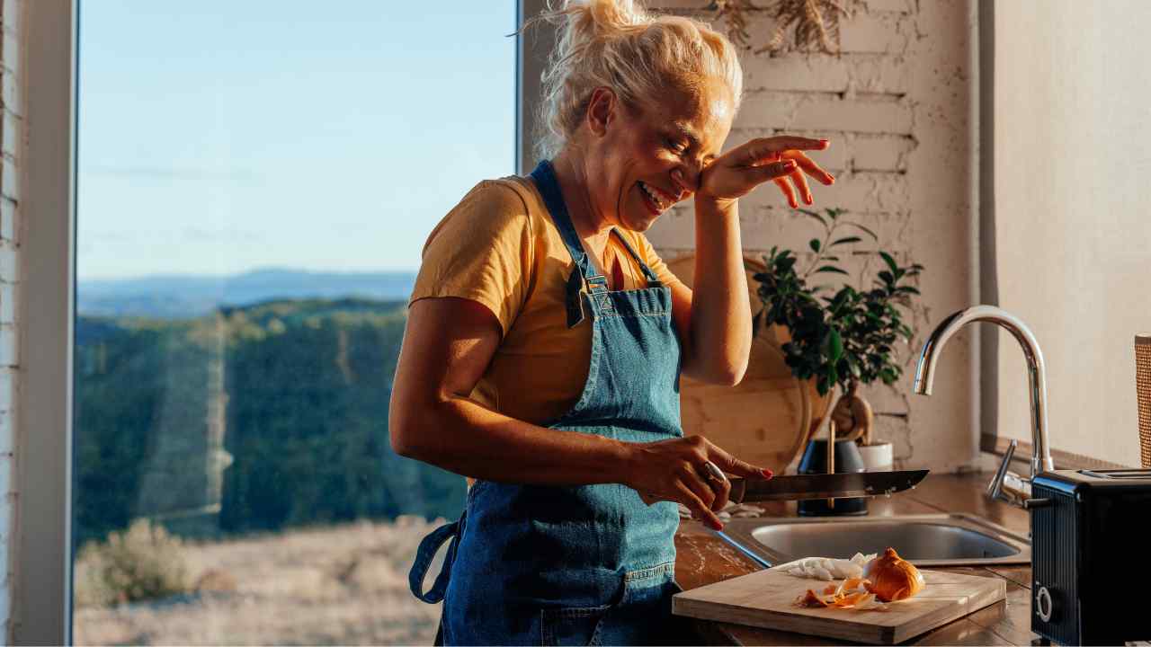 Una donna che piange mentre taglia una cipolla