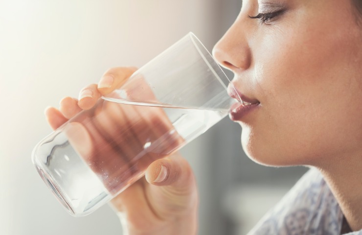 Una donna che beve un bicchiere d'acqua