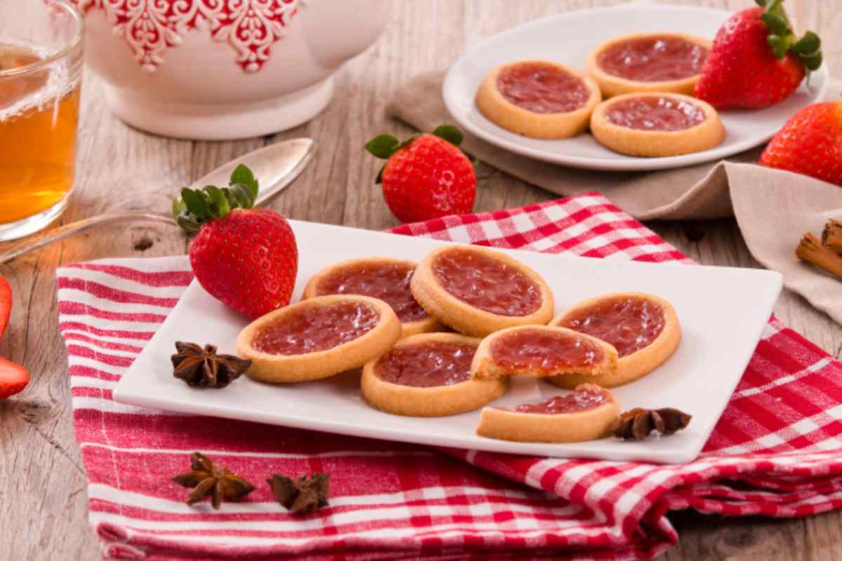 biscotti con marmellata di fragole e accanto delle fragole