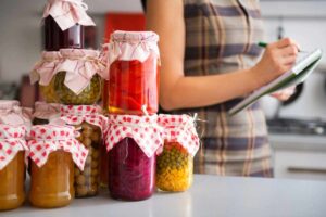 Barattoli con conserve fatte in casa e una donna che scrive