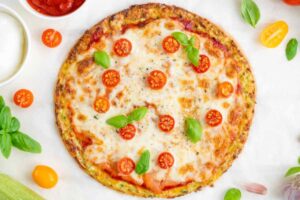 pizza di zucchine con sopra pomodorini freschi e basilico