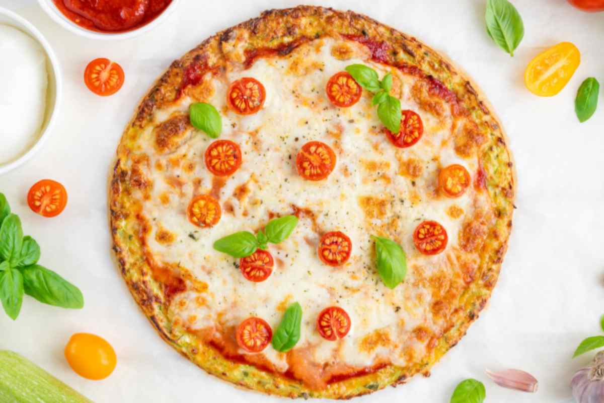 pizza di zucchine con sopra pomodorini freschi e basilico