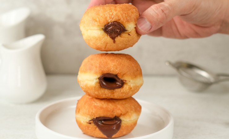 mano che afferra bomboloni al cioccolato
