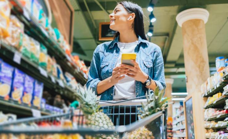 Donna in un supermercato con cellulare in mano