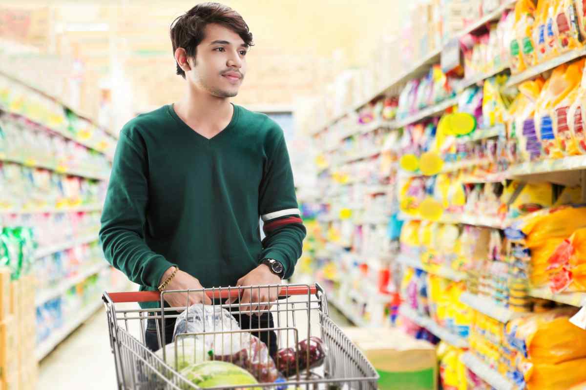 Uomo in un supermercato che spinge carrello con la spesa