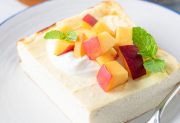fetta di torta allo yogurt con sopra delle pesche tagliate a cubetti