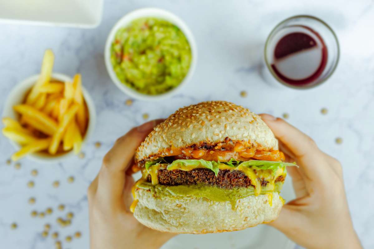 Persona che tiene in mano un hamburger