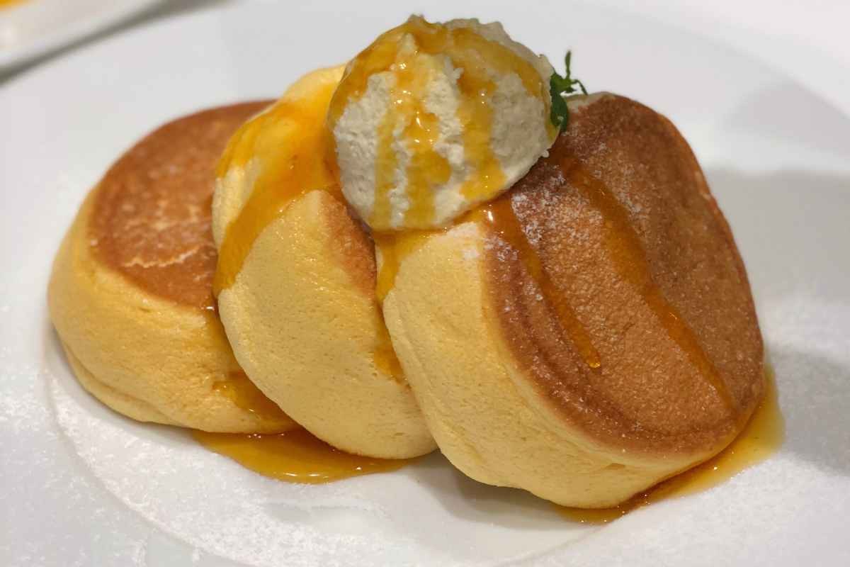 tre pancake nel piattino con panna e miele